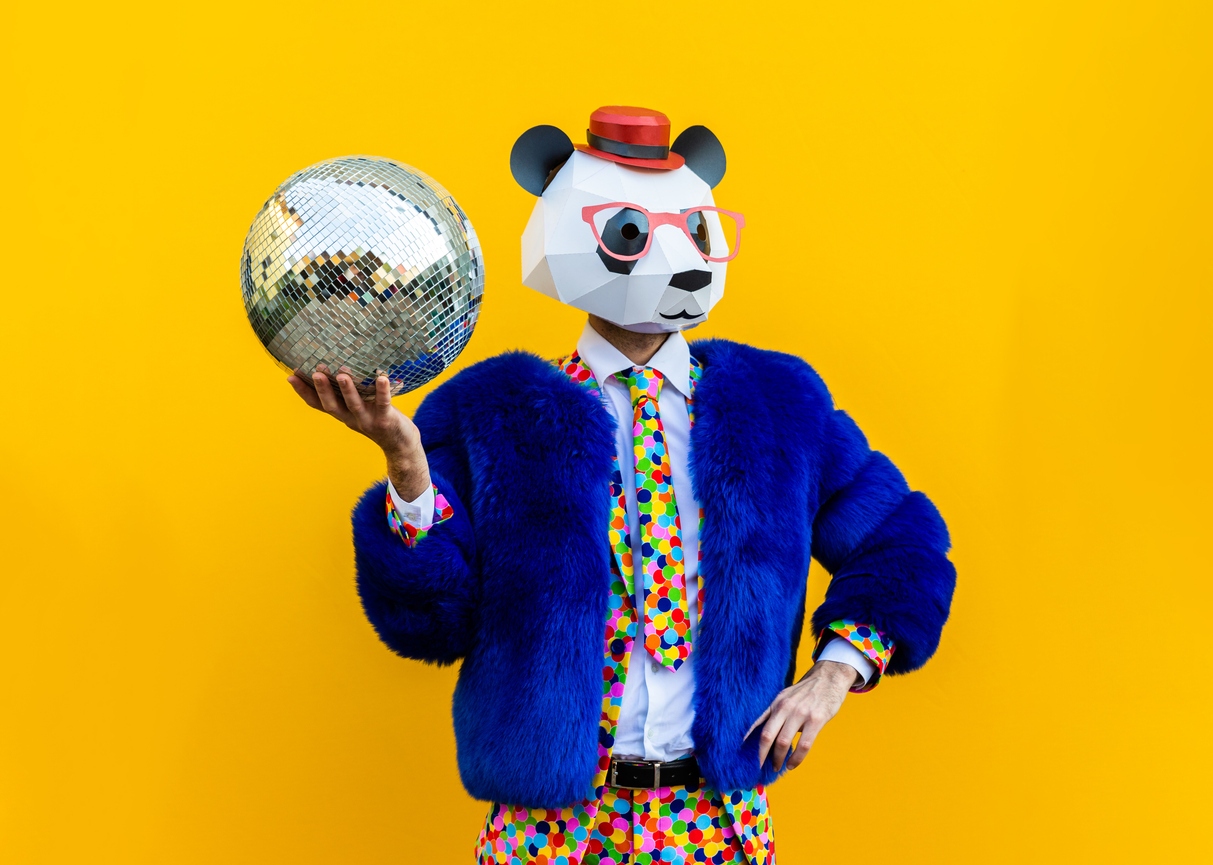 Brand Persona concept; man wearing a panda mask holding a disco ball on a yellow background